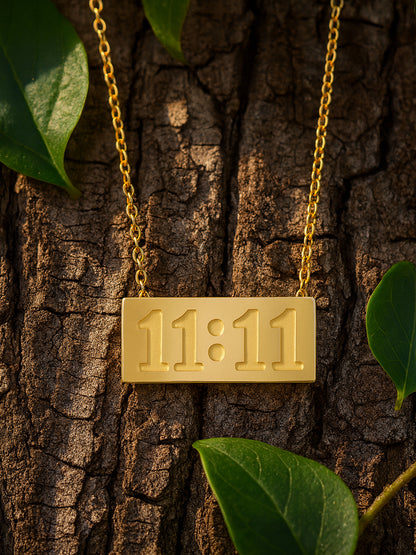 Close-up of a matte finish gold bar necklace for women with 11:11 engraving on a delicate gold chain, draped over natural wood bark.