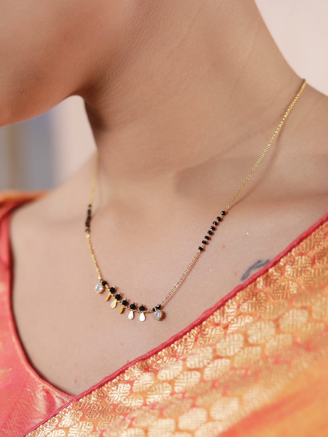 Latest mangalsutra design with delicate gold chain, black beads, and hanging mini gold charms