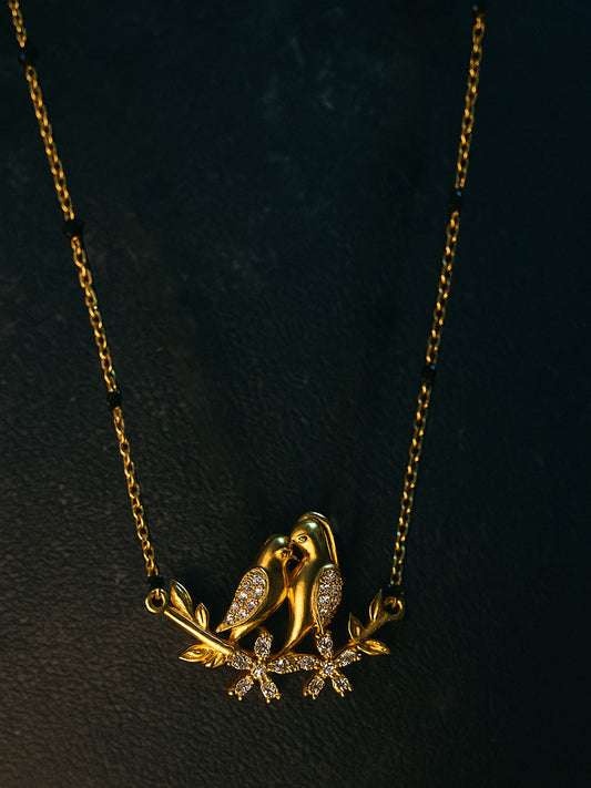 Delicate gold chain with black beads and a diamond-accented twin love birds pendant