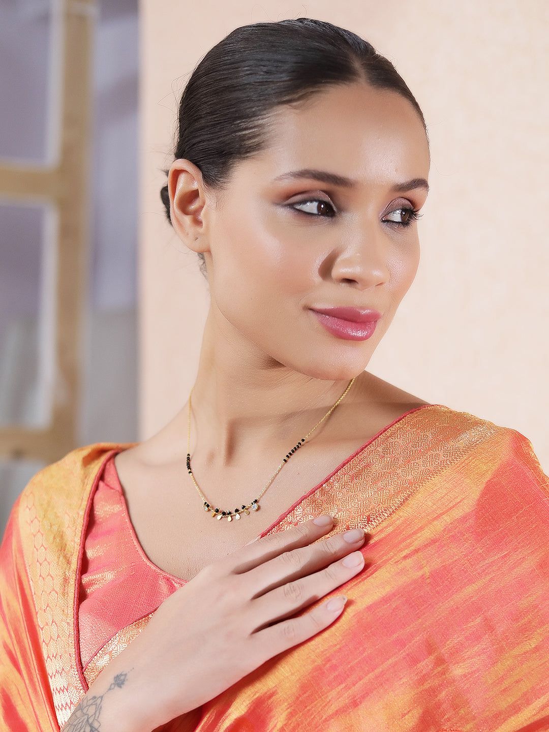 Simple modern mangalsutra design with delicate gold chain and small black beads worn with traditional saree