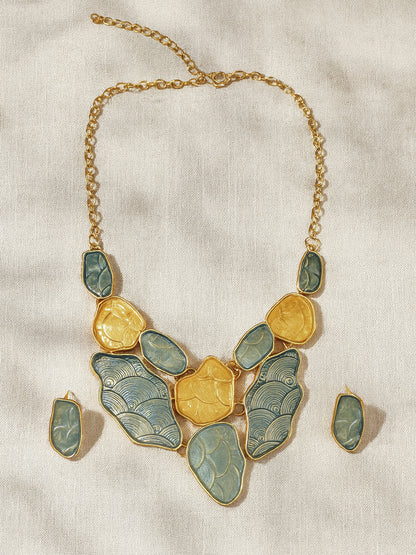 Modern gold choker necklace set against a teal and gold decorative background.