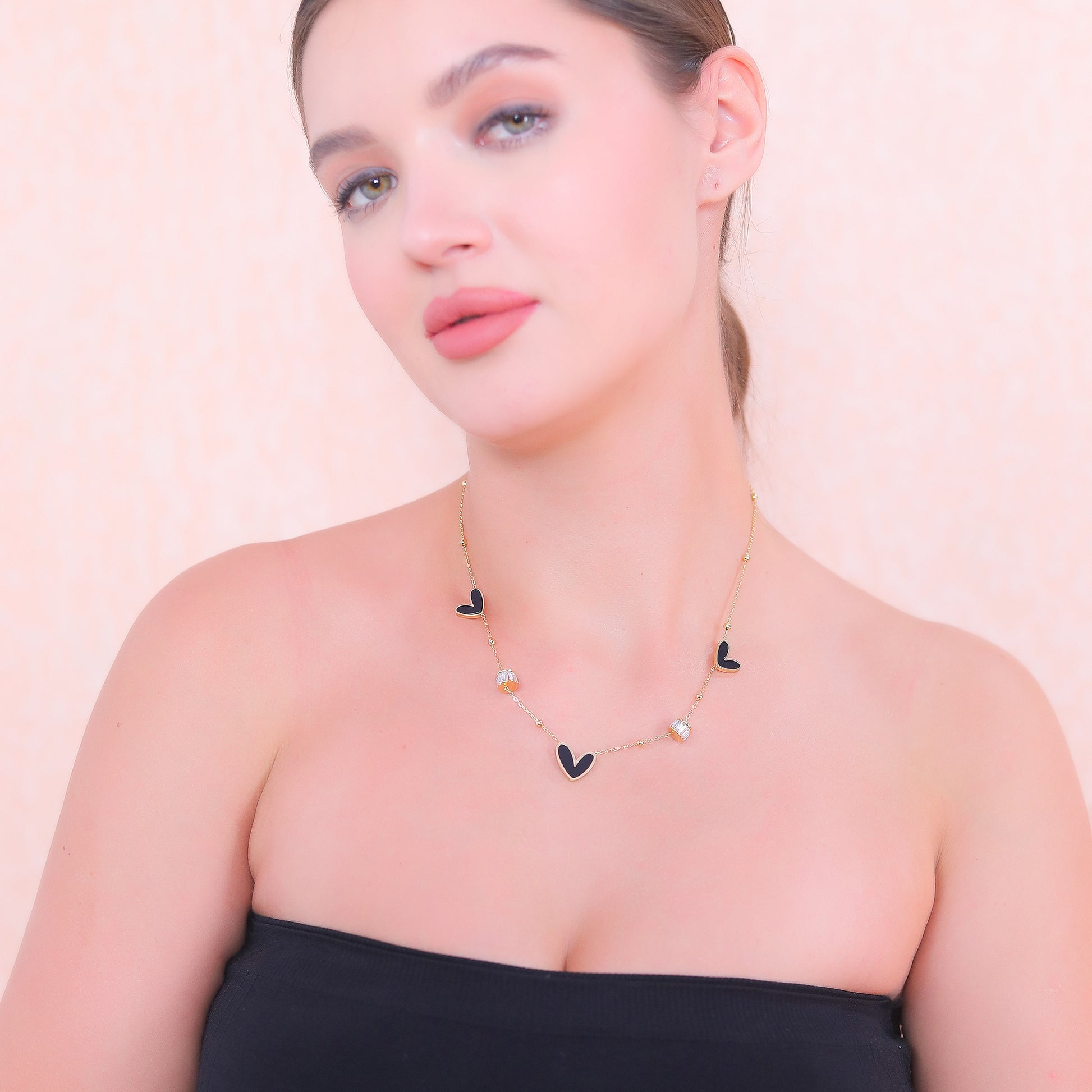 Beautiful modern gold necklace designs with dainty chain and heart charms on a female model