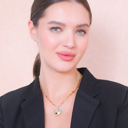 Modern gold necklace designs worn by a model in a black blazer, showcasing a colorful heart-shaped pendant.