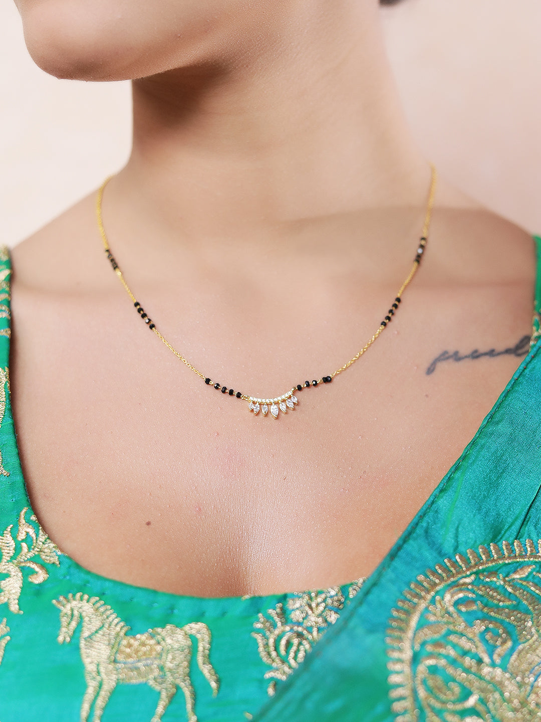 Modern mangalsutra design in gold finish, featuring a delicate black bead chain and a stunning crescent pendant with dangling marquise-cut American diamonds.