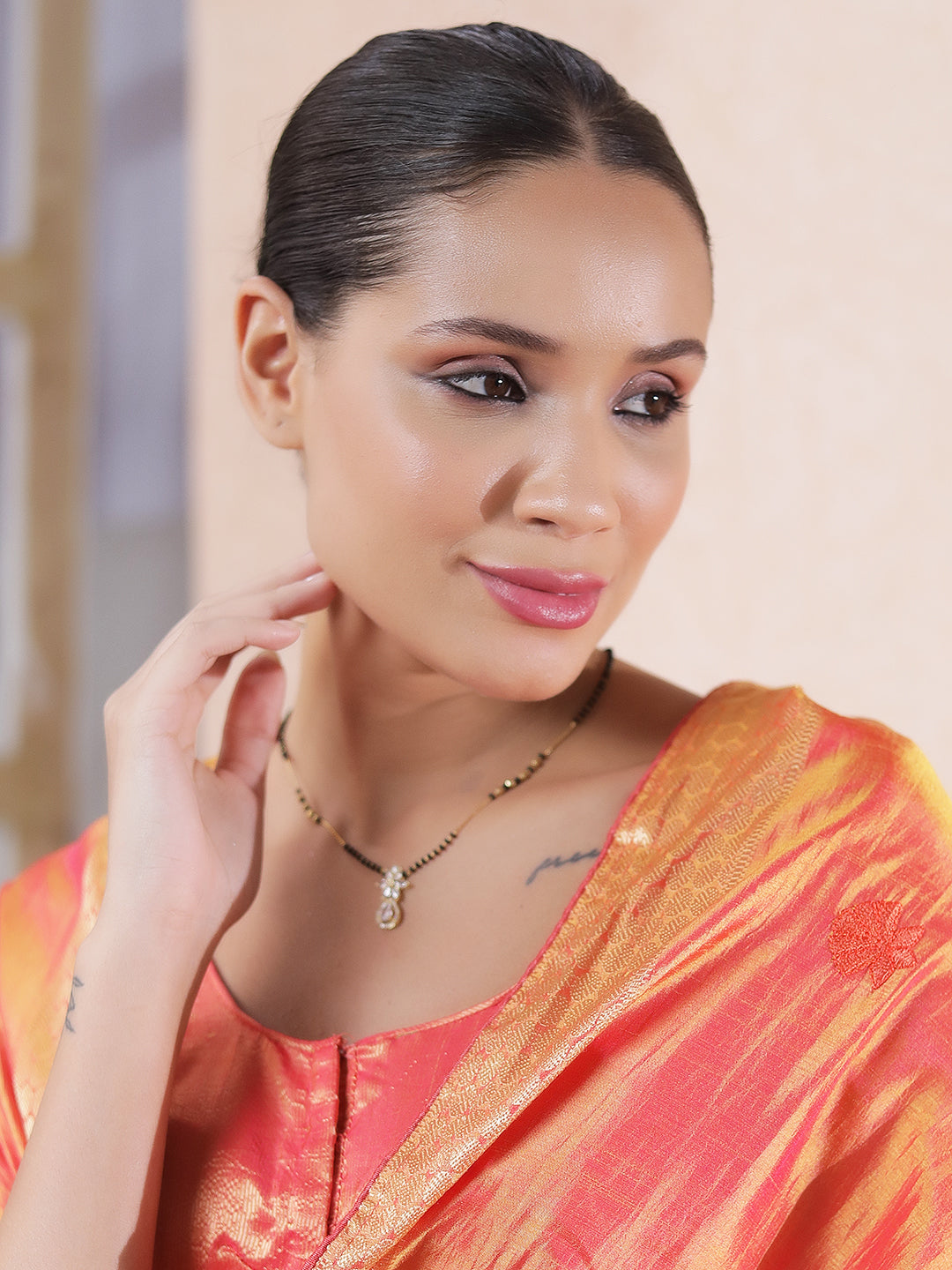 Model wearing a fancy short mangalsutra design with black beads and a floral pendant