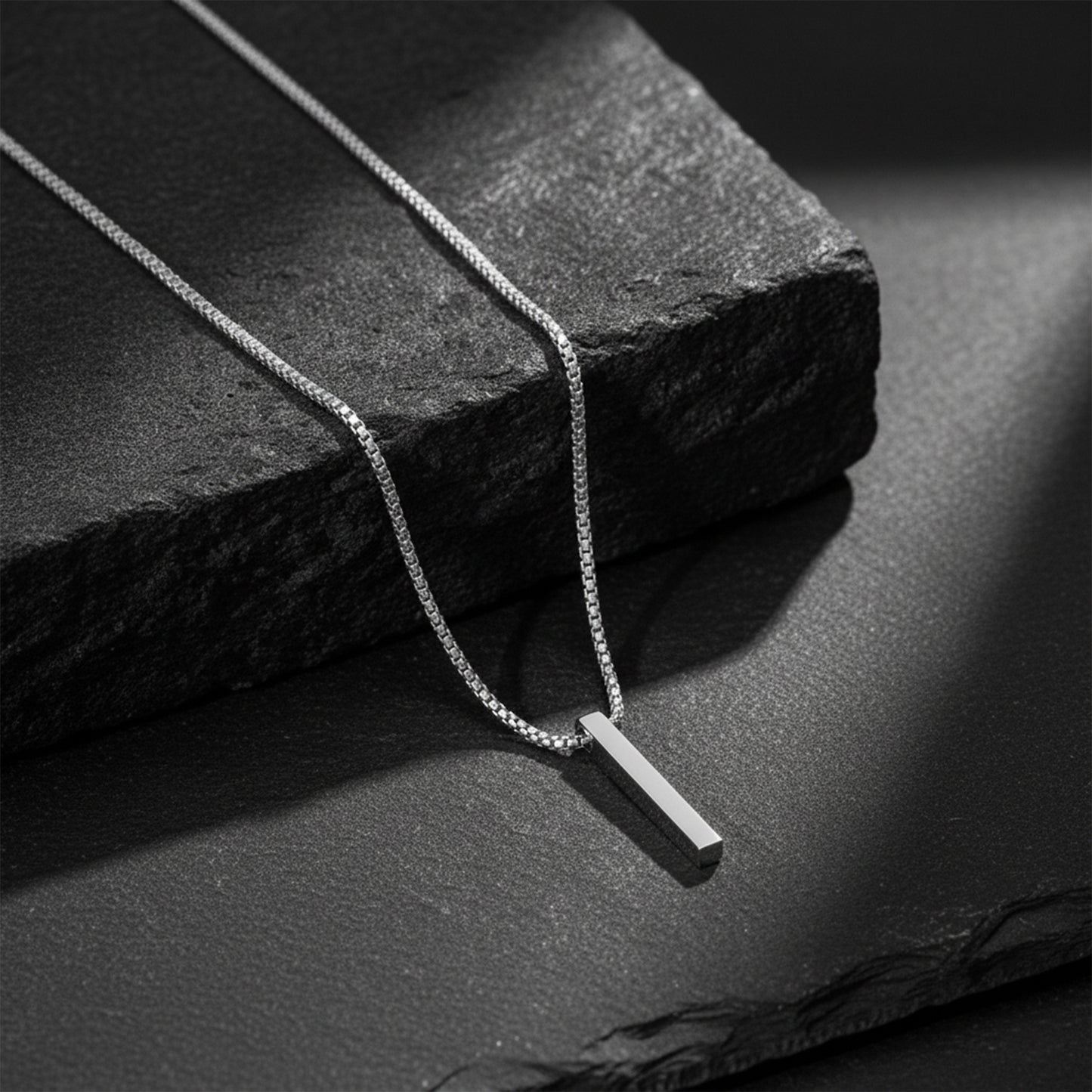 Silver pendant on chain placed on textured stone