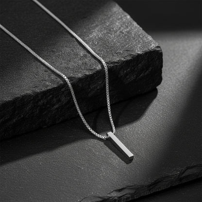 Silver pendant on chain placed on textured stone