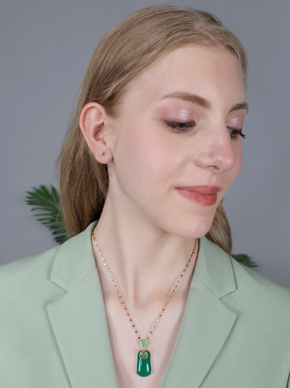 A close-up view of necklace pendant designs gold showing a polished rectangular green gemstone with a gold chain