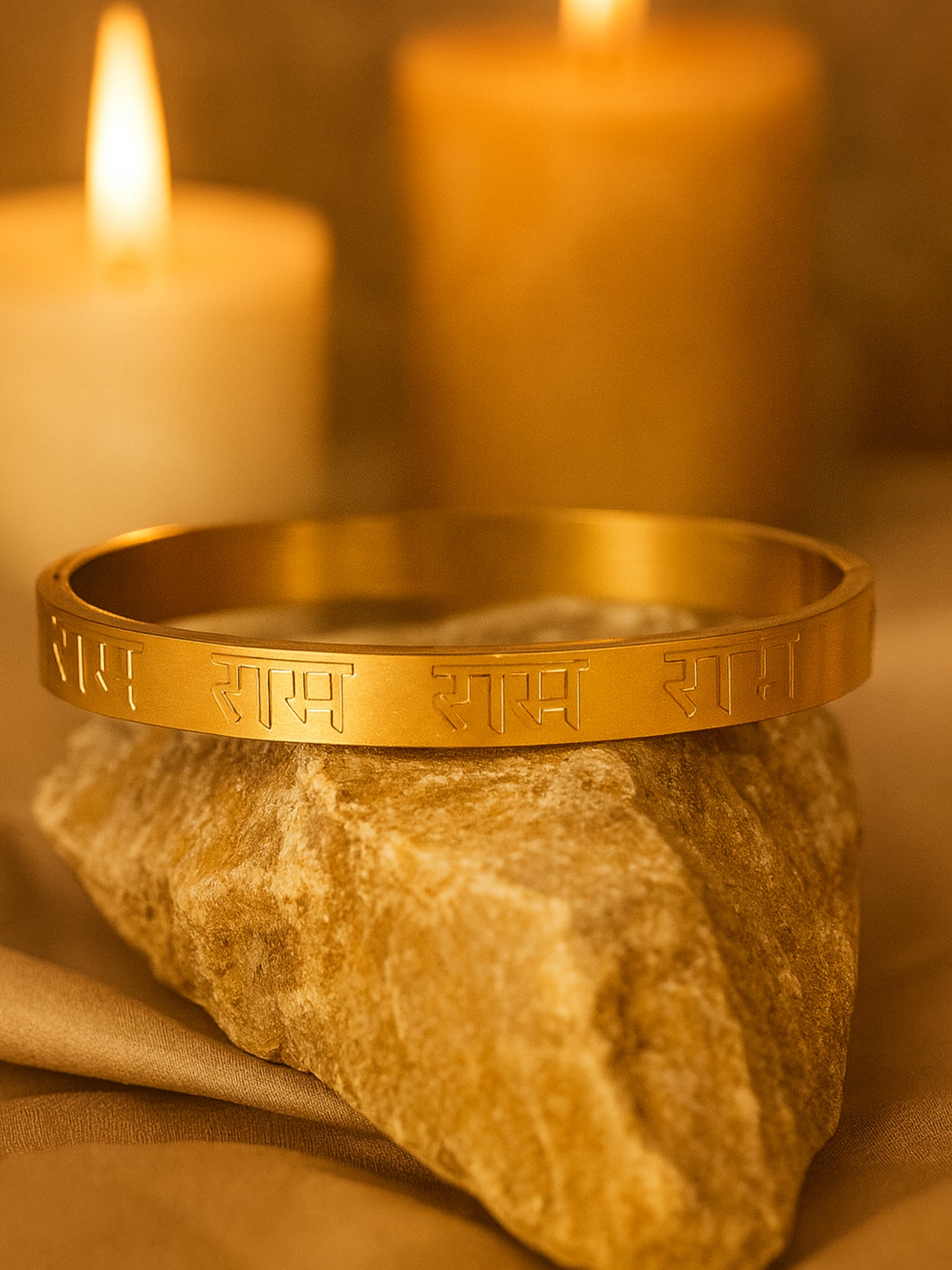 A matte finish gold bracelet for women for daily wear engraved with "Ram" in Hindi, resting on a stone.