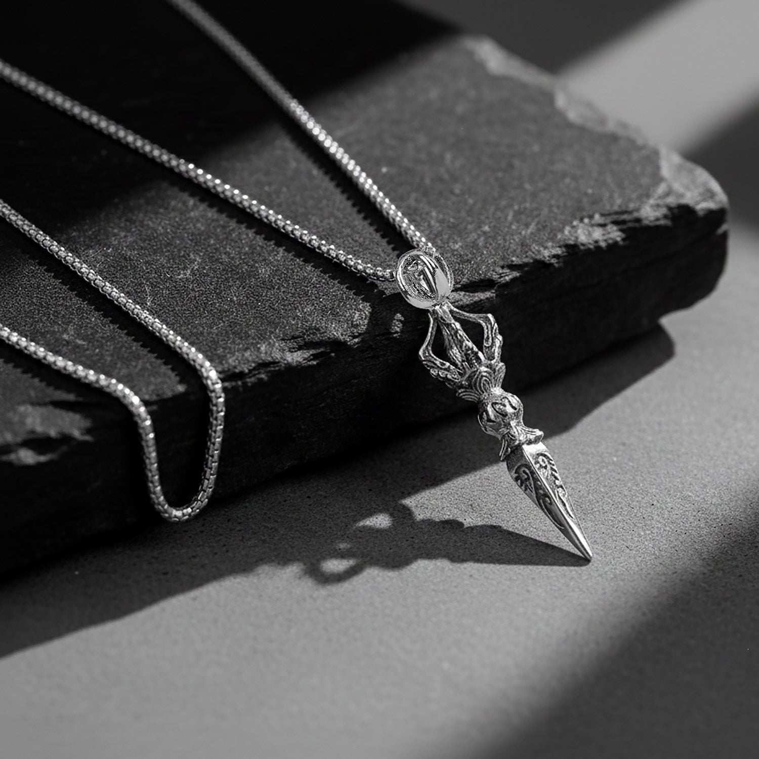 Silver chains for men with detailed pendant on a textured dark surface