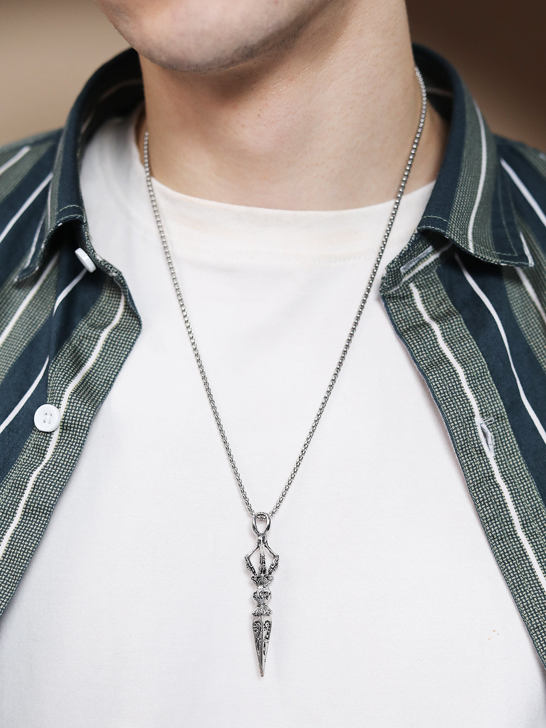 Sterling silver necklace with detailed pendant on white T-shirt
