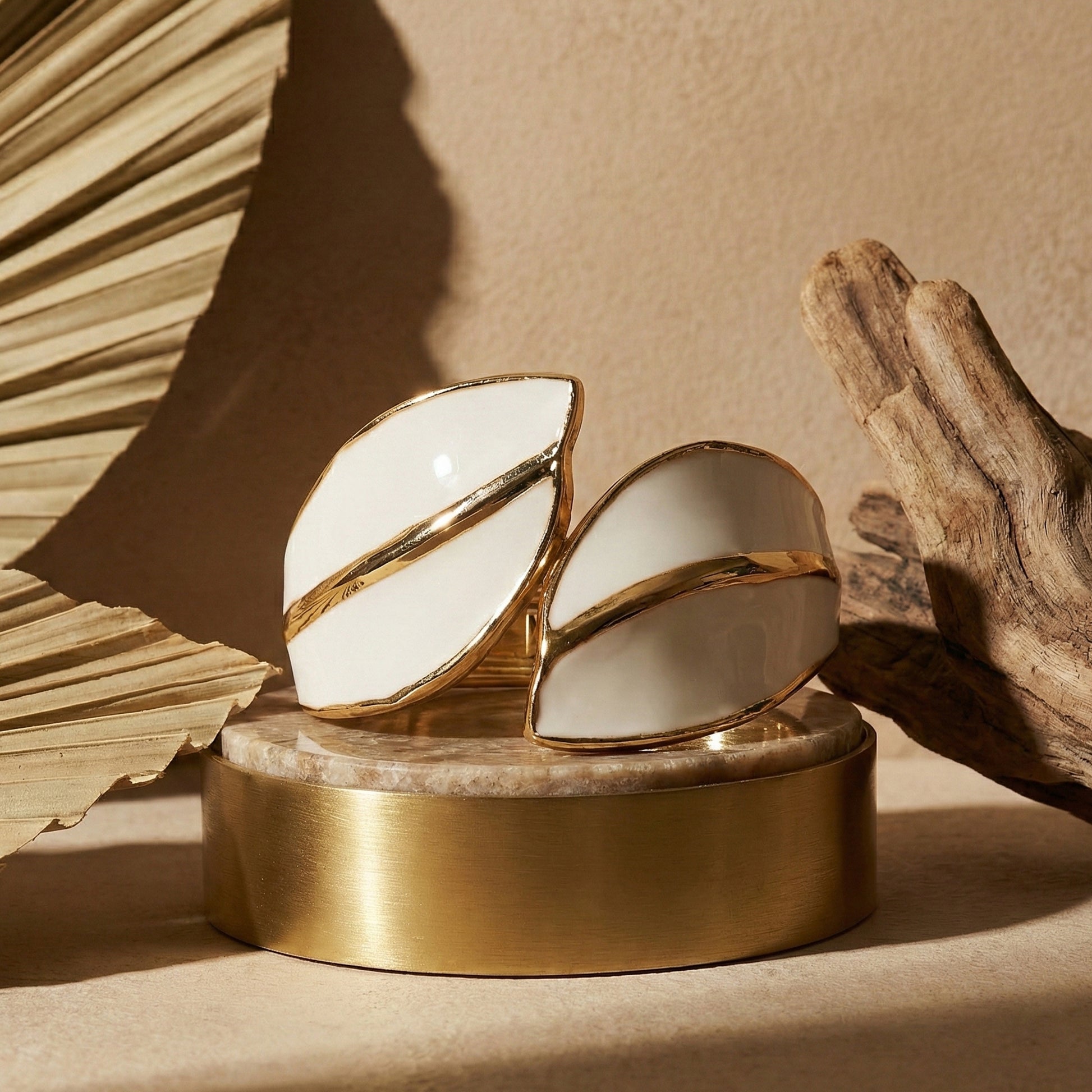 simple bracelet for women featuring a minimalist gold and white leaf motif on a decorative pedestal.