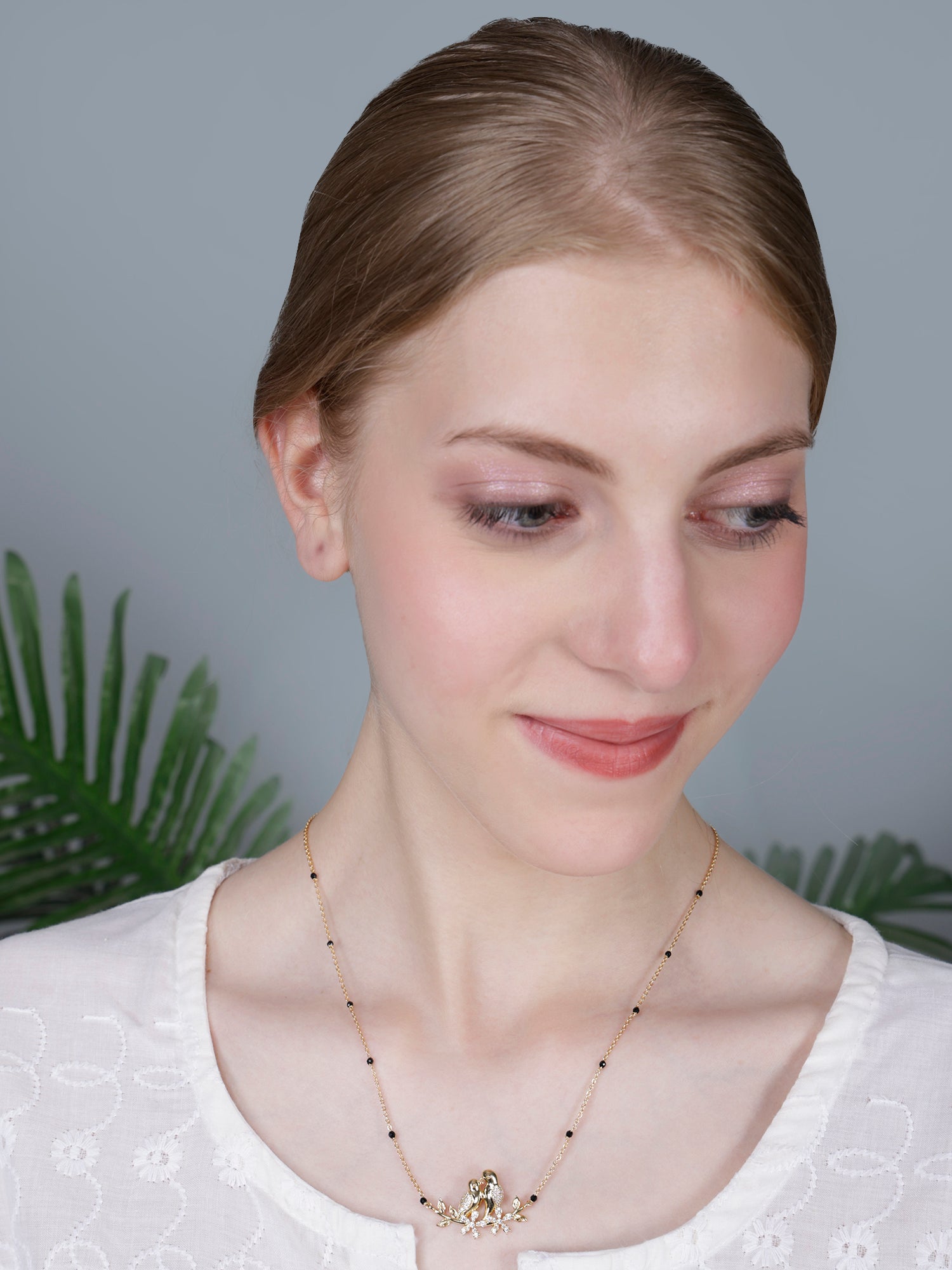 Simple and sophisticated daily wear mangalsutra design in gold with a minimalist love bird motif, shown on a model