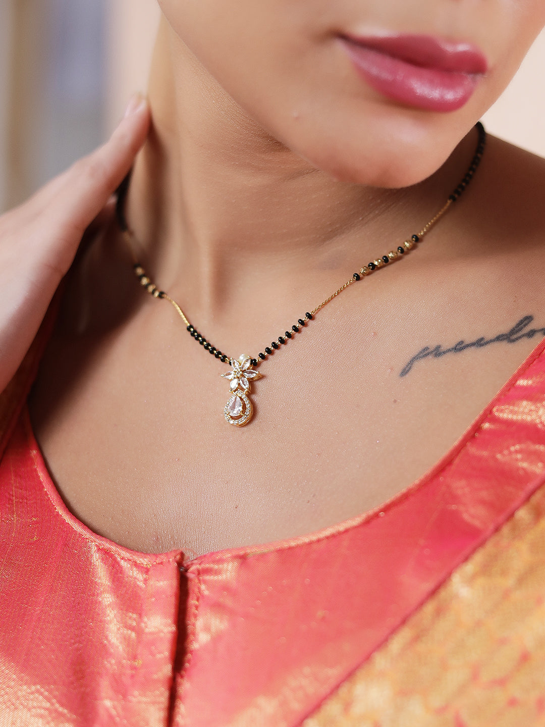 simple modern mangalsutra design with black beads and a sleek floral gold pendant close up