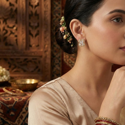 Detailed view of a small gold earring from a matching jewelry set, worn by a model with an elegant updo.