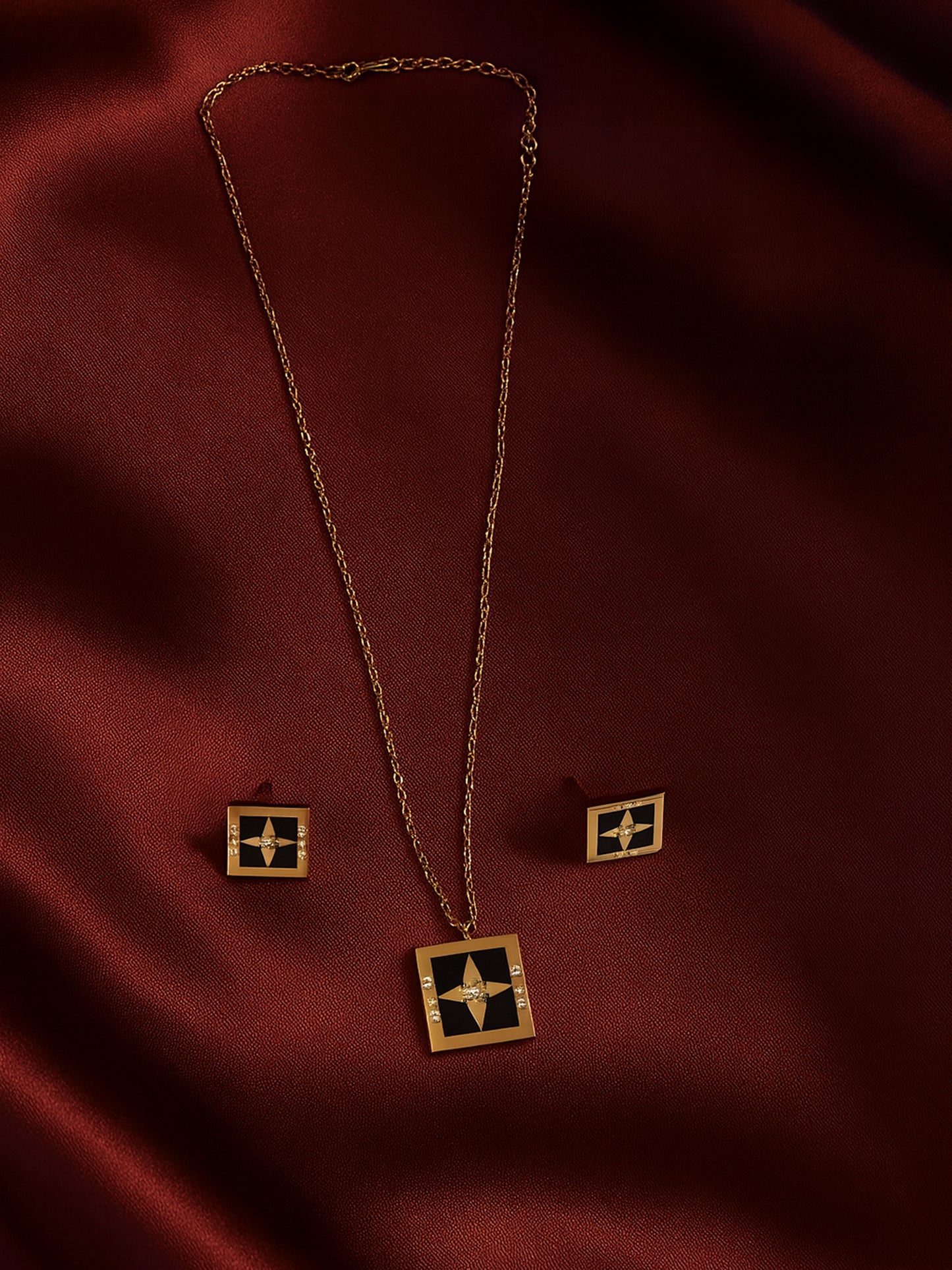 Small gold necklace design featuring a black enamel square pendant with a compass star and rose gold-tone chain and earring