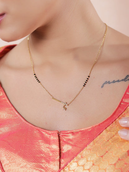 Latest mangalsutra design with a minimal gold bar pendant, solitaire drop, and black beads worn with a traditional outfit.