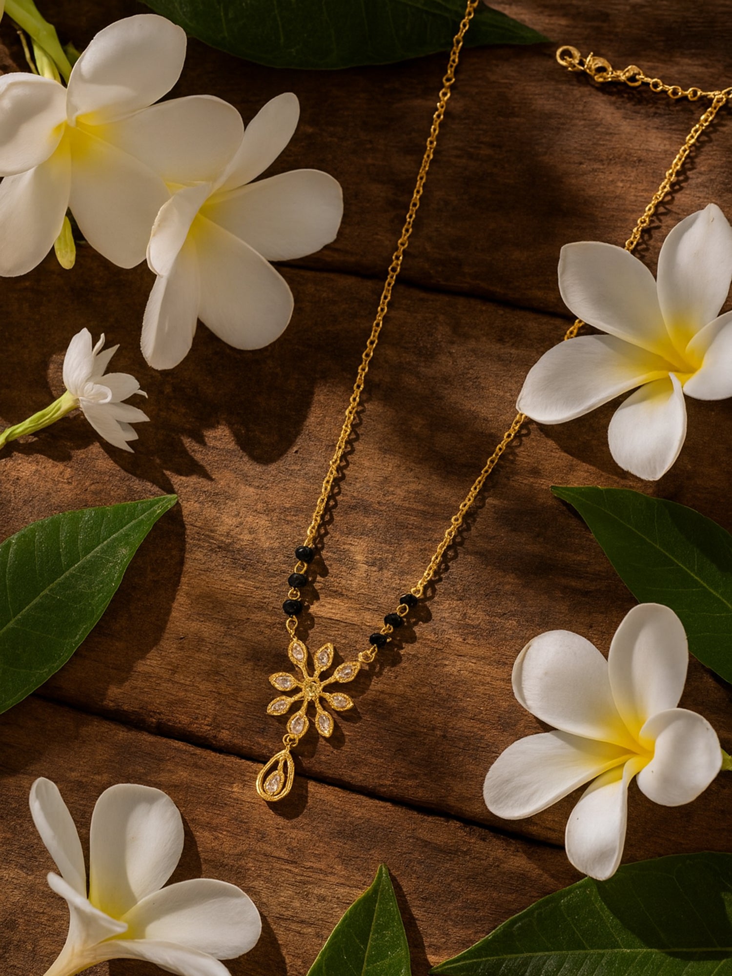 Elegant mangalsutra design featuring a sparkling diamond/CZ floral motif and teardrop pendant on a gold chain with black beads