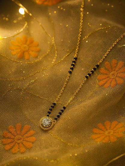 Close-up of a glamorous gold plated mangalsutra design with a solitaire stone, photographed in warm, bright light