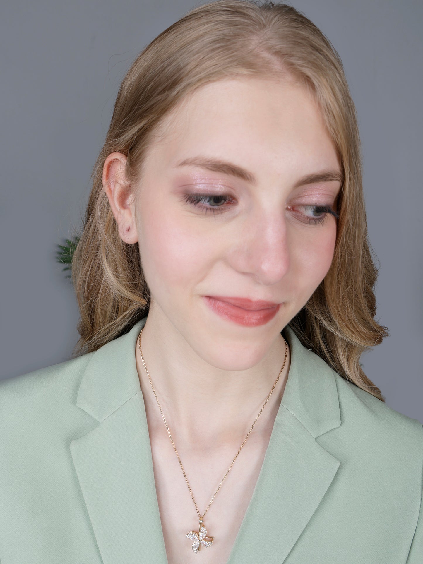 Woman wearing elegant gold long necklace designs featuring a rotating floral windspinner pendant 