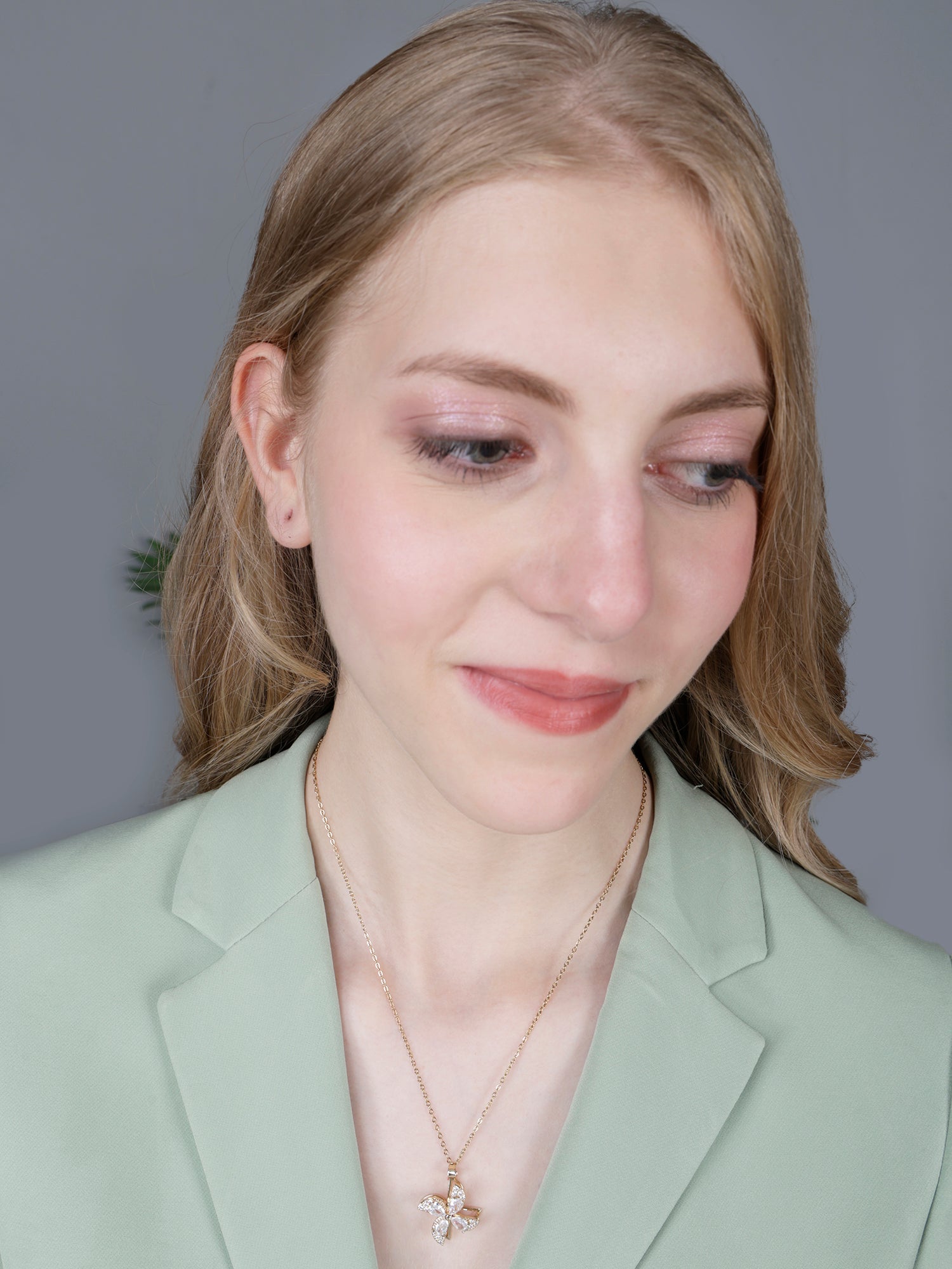Woman wearing elegant gold long necklace designs featuring a rotating floral windspinner pendant 