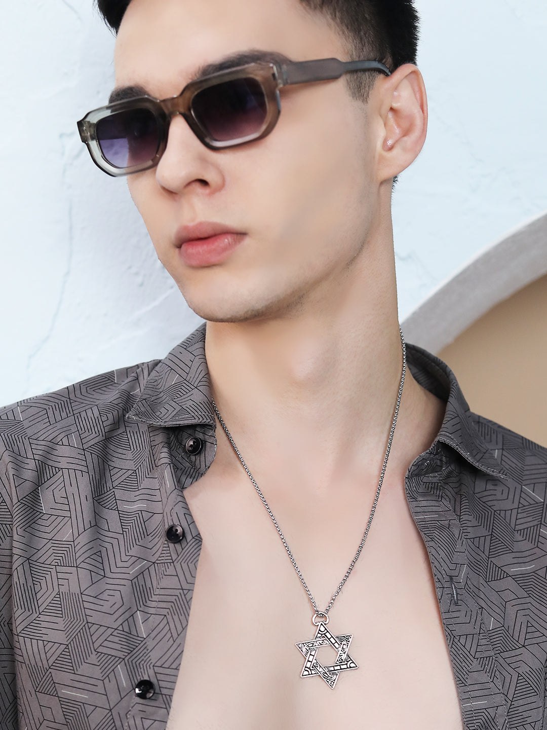 Sterling silver necklace with star pendant worn by a model in an open shirt