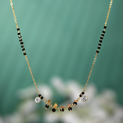 Artificial mangalsutra with gold plated chain, black beads, and crystal stone charms