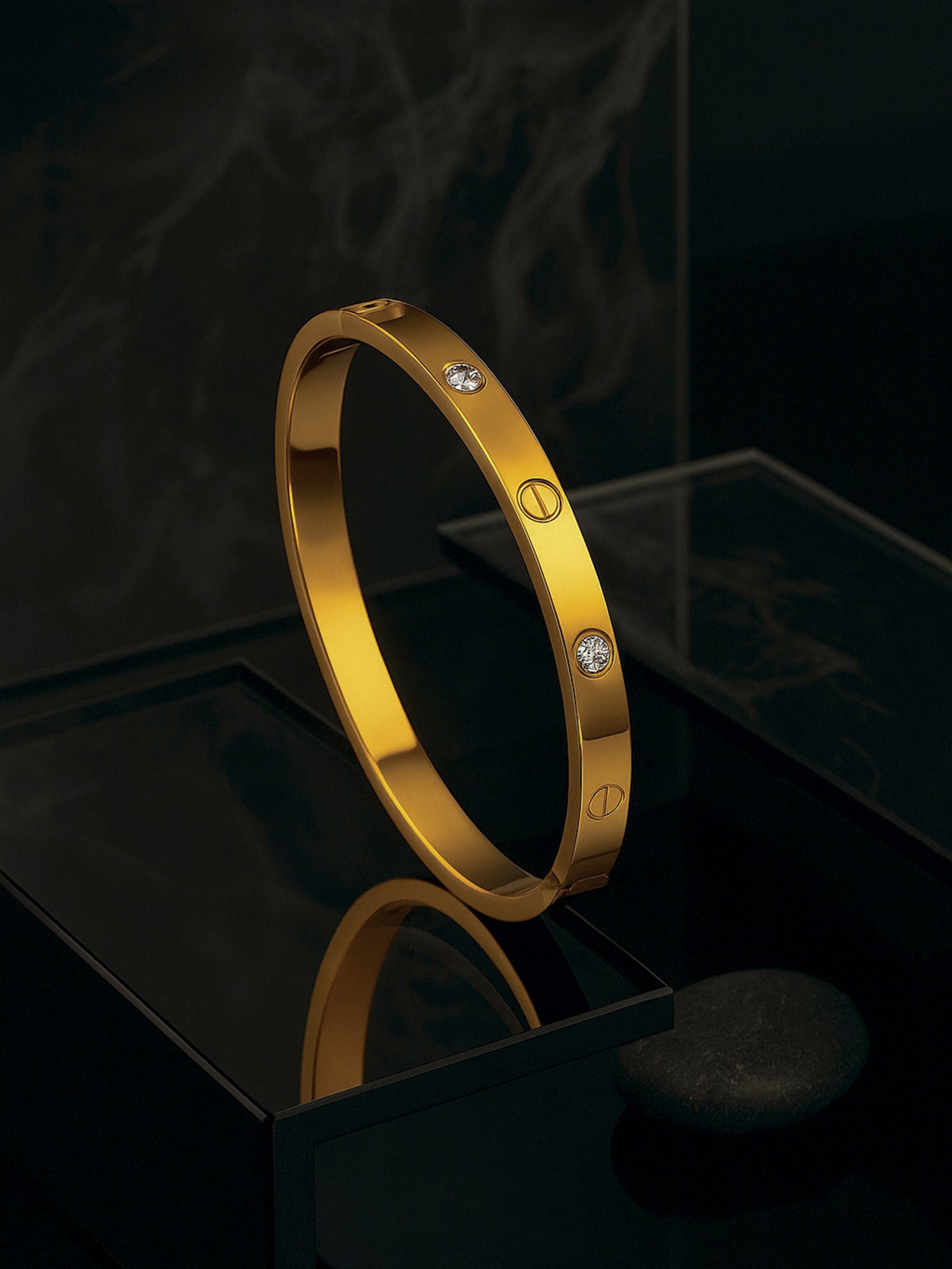 A stylish gold bracelet design for women featuring embedded crystals, displayed on a reflective black pedestal.