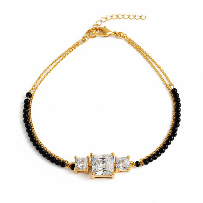 Stylish mangalsutra design bracelet with gold chain, black beads, and three stone centerpiece.
