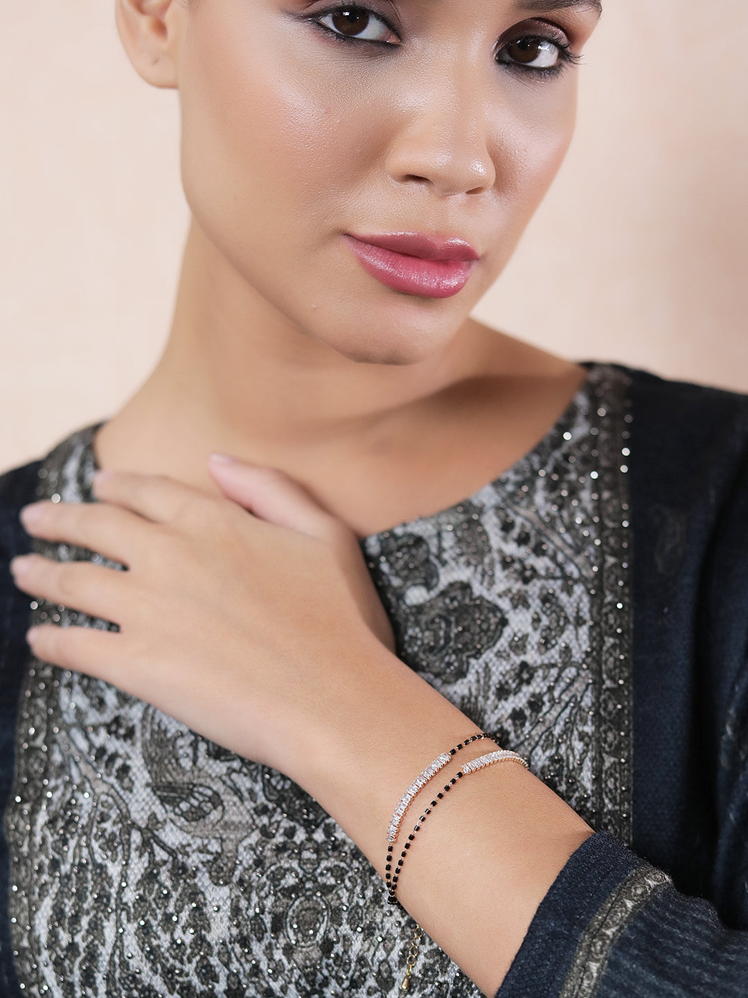 Woman wearing a stylish mangalsutra bracelet design with black and gold beads.