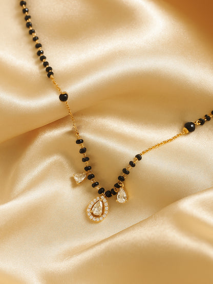 Minimal gold mangalsutra with black beads, fine gold chain and teardrop crystal pendant on satin fabric