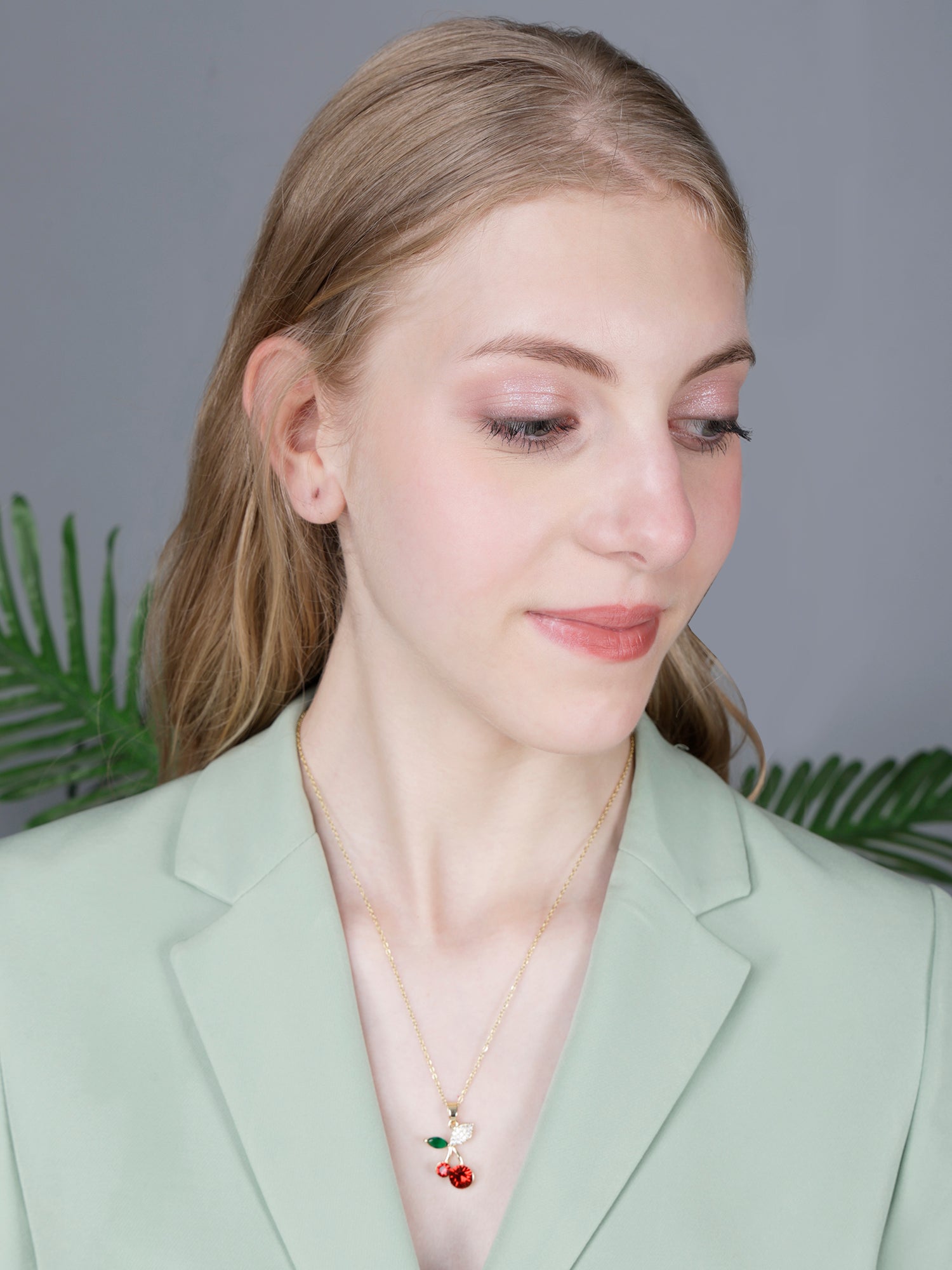 A professional look styled with gold long necklace designs and a vibrant red crystal fruit pendant