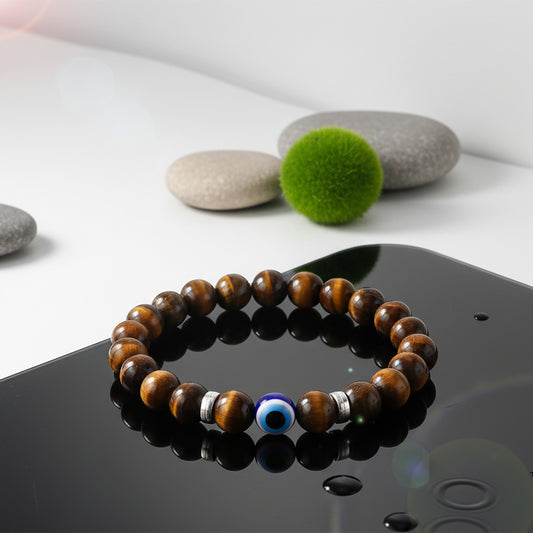 Wooden bracelet with blue evil-eye bead displayed on reflective stones