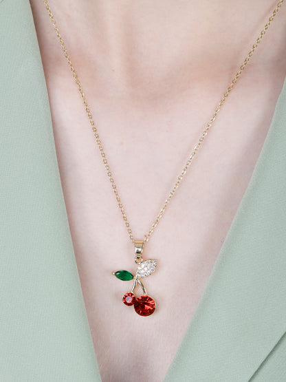 A model wearing a necklace pendant designs gold featuring a crystal cherry charm with red and green stones.