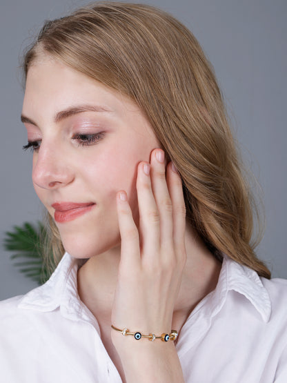 A gold plated bracelet for ladies styled with a casual white blouse and natural makeup.