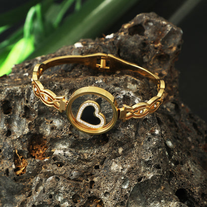 Elegant gold hand bracelet for women with heart-shaped design displayed on a textured stone background