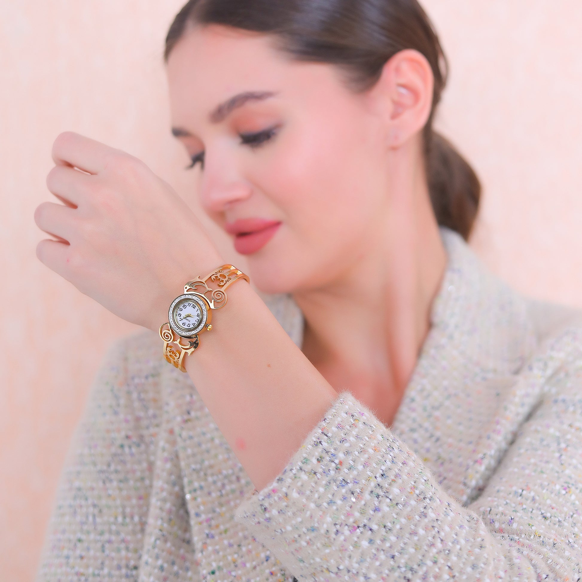 A model wearing a stylish gold bracelet design for women featuring an integrated watch and intricate cutouts.